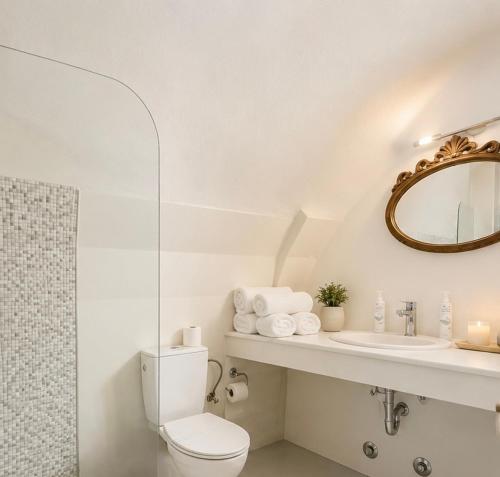 a white bathroom with a toilet and a sink at Santorini Theasis Suites in Imerovigli