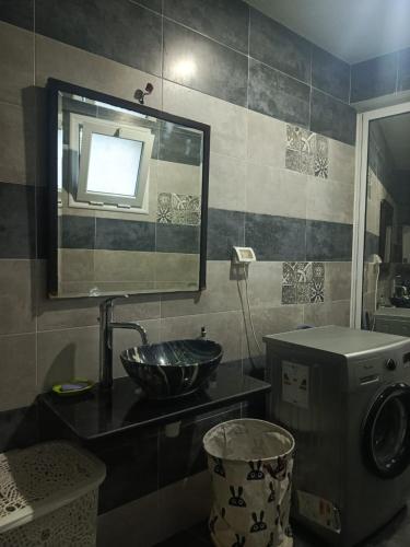 a bathroom with a sink and a mirror and a washing machine at maison entre forêt et mer in Raʼs al Jabal