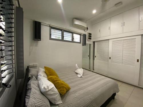 a bedroom with a bed with a yellow blanket on it at Muaicolo House in Suva