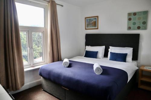 a bedroom with a large bed with blue sheets and a window at City Centre Guest House - Gloucester Park in Gloucester