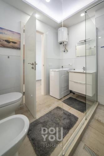 a white bathroom with a sink and a toilet at Holiday Apartments Oasis in Los Cristianos