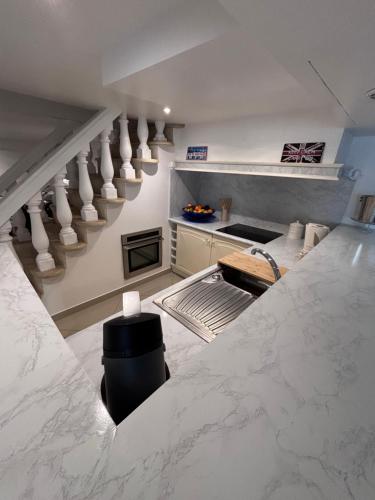 a kitchen with a staircase with white marble counter tops at Appartement Carreira in LʼIsle-Adam
