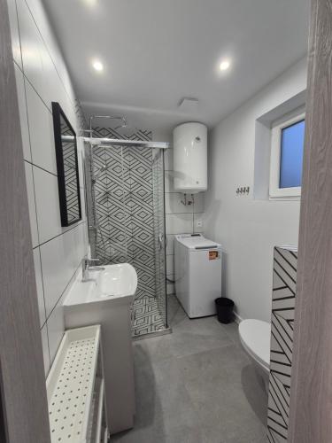 a white bathroom with a sink and a toilet at Domki na Polnej in Grzybowo