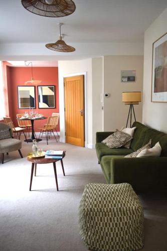 a living room with a green couch and a table at Town Centre - Elegant Stylish Apartment in Shrewsbury