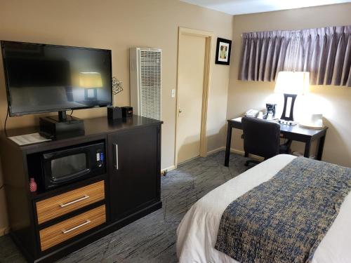 a hotel room with a bed and a flat screen tv at Monroe Motel Near Seattle Everett WA in Monroe