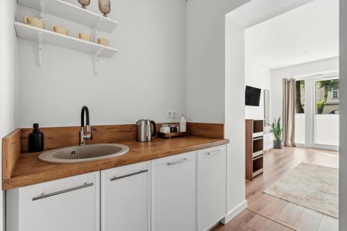 a kitchen with white cabinets and a sink at Spacious Studio Near Station Klaipėda in Klaipėda