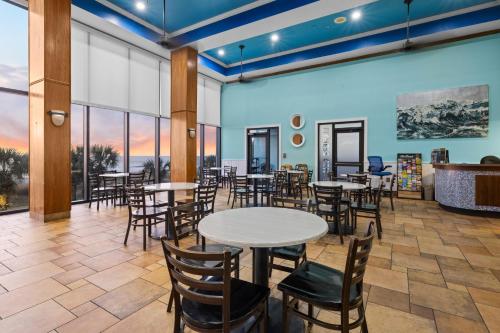 a dining room with tables and chairs and windows at Monterey Bay Suites in Myrtle Beach