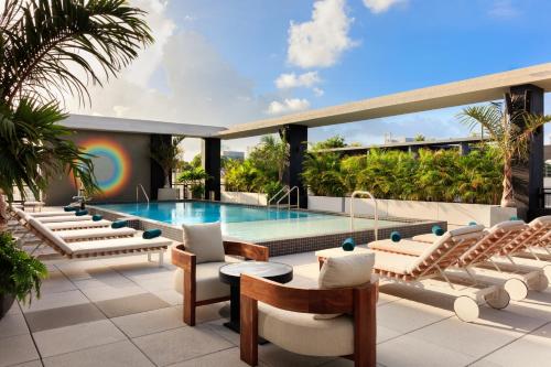 a pool on the roof of a building with lounge chairs at Moxy Miami Wynwood in Miami