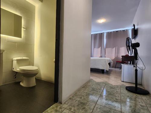 a bathroom with a toilet and a room with a bed at Hotel Marsal in Antofagasta