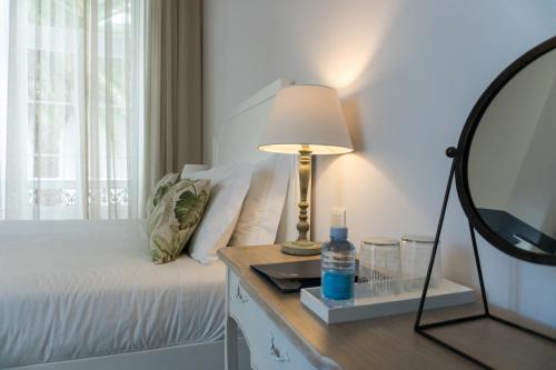 a bedroom with a bed with a lamp and a mirror at Casa das Palmeiras Charming House - Azores 1901 in Ponta Delgada