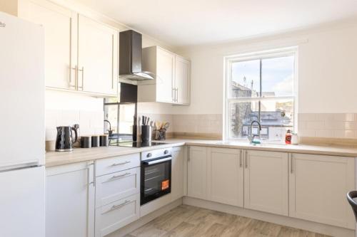 a white kitchen with white cabinets and a window at Harbour View in Whitehaven
