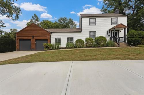 a large white house with a garage and a driveway at Stylish KC FarmhouseHugeFencedYard in Merriam