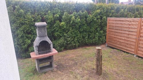 a outdoor oven sitting in a yard next to a bush at Domek nad jeziorem in Dorotowo