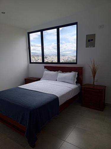 a bedroom with a large bed with two windows at Apartamentos Latacunga in Latacunga