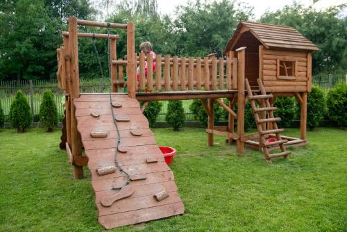 a child is playing on a wooden playground at Hotel Novum & Spa in Niepołomice