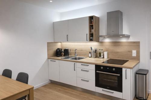a kitchen with white cabinets and a sink and a stove at Apartmán Javorná Living in Čachrov