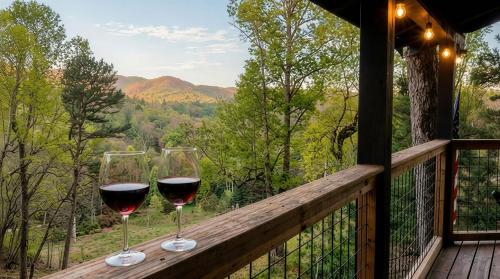 two glasses of wine sitting on a wooden rail on a balcony at UnBearably Cozy - pool table, fire pit, central location in Bryson City