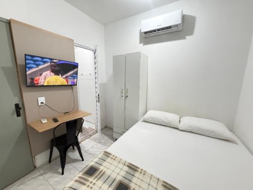 a bedroom with a bed and a desk with a tv at Mini Ap no derby com Garagem in Sobral