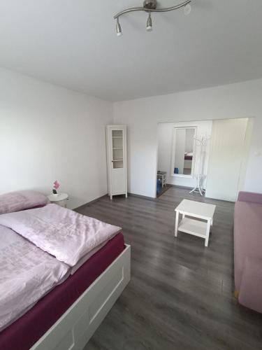 a white bedroom with a bed and a table at 1-room apartment in Nitra