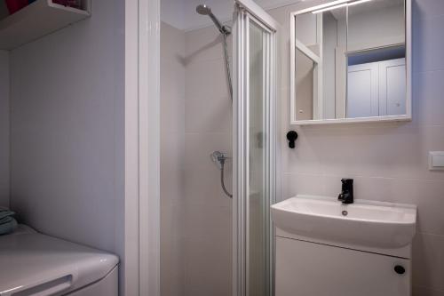 a white bathroom with a sink and a shower at Acogedor studio a 10min de la playa in Torredembarra