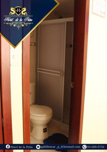 a bathroom with a white toilet in a room at Hotel de la Peña in Ambato