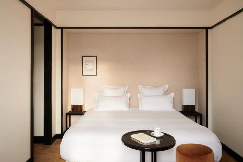 a bedroom with a large white bed with a table at Hôtel Atlas in Paris