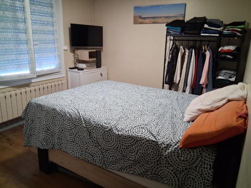 a bedroom with a bed and a dresser with clothes at Maison proche bassin et océan in Arès