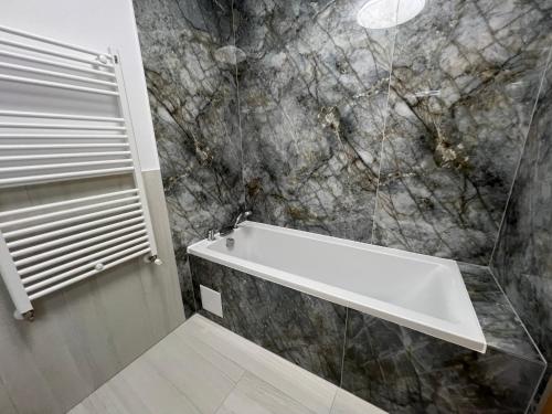 a bathroom with a white bath tub and marble walls at Luxury Central Monarch Residence Apartment Sleeps 5 in Timişoara
