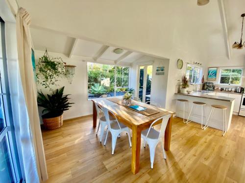 a kitchen and dining room with a wooden table and chairs at Tairua Tides - Relaxed Coastal Retreat in Tairua