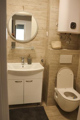 a bathroom with a sink and a toilet and a mirror at MODERN ESCAPE apartment with garage in Split