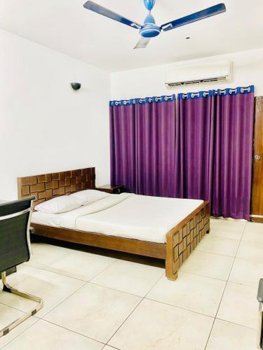 a bedroom with a bed and purple curtains at Elegant Residence Guest House in Dhaka