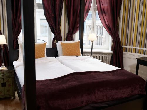 a bedroom with a canopy bed with red curtains at Hotel Kung Carl, WorldHotels Crafted in Stockholm
