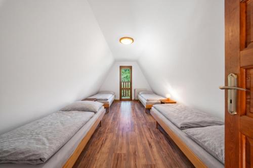four beds in a room with white walls and wooden floors at Horská chata ERIK in Levoča