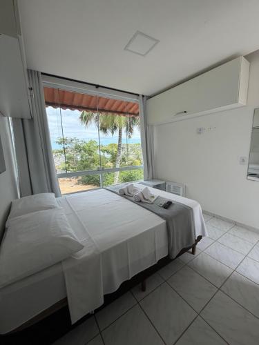 a bedroom with a bed and a large window at Pousada Caravelas in Guarapari