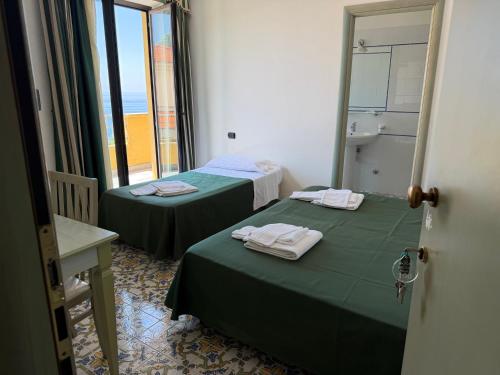 two beds in a small room with a window at Belvedere Blu b&b & beach in Belvedere Marittimo