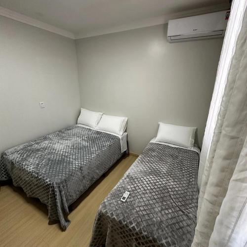a bedroom with two beds and a window at Loft Lux SM Chapecó com excelente localização! in Chapecó