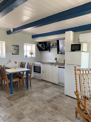 a kitchen with a table and a white refrigerator at Uggerhøjvej Gårdhygge in Hjørring