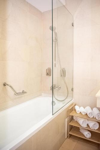 a bathroom with a shower and a tub with towels at Ariana Deluxe Suites in Bucharest