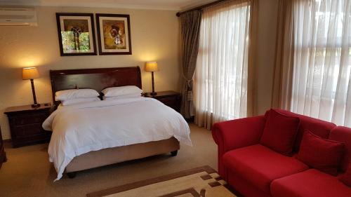 Jubilee Lodge Guest House في جوهانسبرغ: غرفة نوم بسرير واريكة حمراء