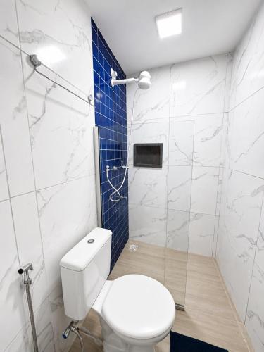 a bathroom with a white toilet and a blue tile wall at Manaira Suite 01 in João Pessoa