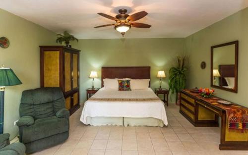 a bedroom with a bed and a fan and a chair at Casa Pura Paz in Puntarenas