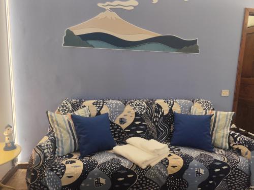 a couch with blue pillows in a living room at Casa vacanze SALSEDINE in Mascali