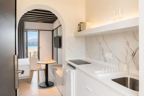 a kitchen with white counters and a table and a sink at Veneto Sea View Apartments in Stalís
