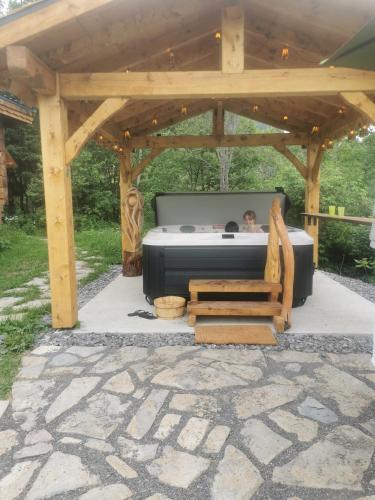 a man sitting in a bed under a gazebo at Gîte de l'herboriste spa et vue sur la fjord in Sainte-Rose-du-Nord