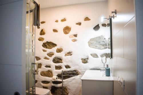 a bathroom with a stone wall with a shower at Casa El Nido, Agaete in Agaete