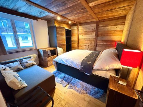 a bedroom with a bed in a room with wooden walls at Alpine Chic Escape with Spa & Panoramic Views in Engelberg