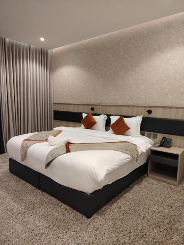 a bedroom with a large bed with white sheets and orange pillows at فندق لوشال LECHAL Hotel in Medina