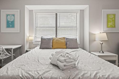a white bedroom with a bed with a person laying on it at Stay at Cypress Cottage in Charleston