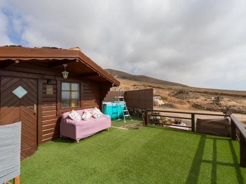 a small house with a pink couch on the grass at La Maxada Luz Maria in El Cotillo