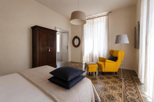 a bedroom with a bed and a yellow chair at Casa Vacanza Baragiola4 - Hotel San Giuseppe Group in Cernobbio
